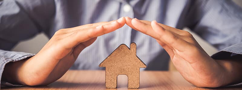 Kädet puisen talon suojana. Vahvat salasanat antavat vastaavasti turvan tärkeille tiedoillesi.