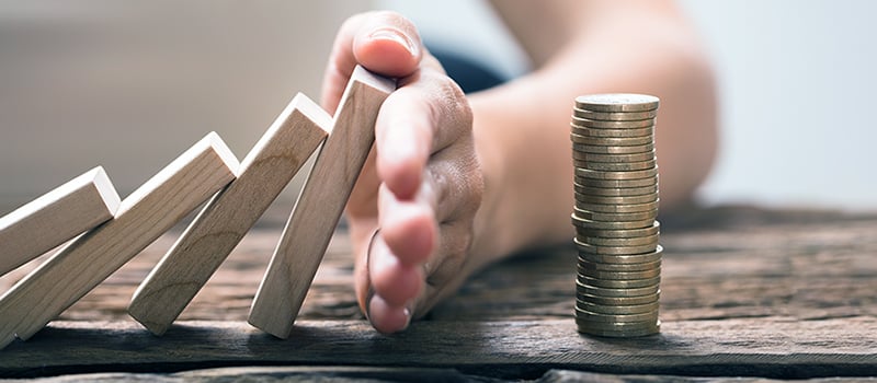 Yritysvakuutus voi suojata taloudellisilta vahingoilta. Käsi estää rahapinoa kaatumasta.912