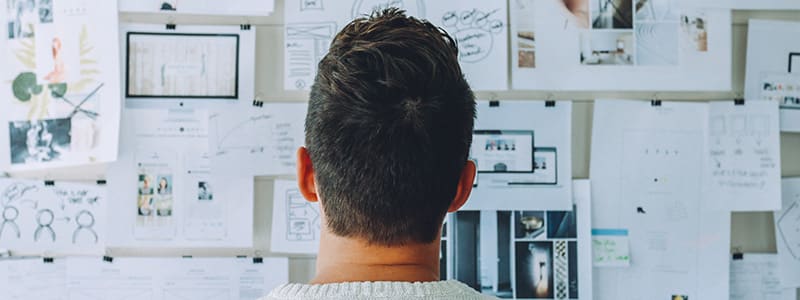 Mies ilmoitustaulun edessä pohtimassa yritysmuodon valintaa.