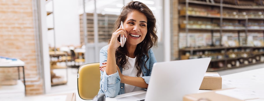 Verkkokauppias puhuu puhelimessa tietokoneen ääressä.