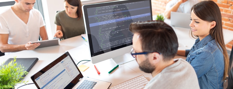 Verkkosivujen alusta vaikuttaa myös suunnitelman toteuttamiseen. Nettisivujen rakentajat työskentelevät tietokoneen ääressä.