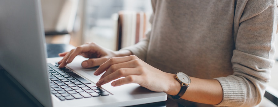 Nettisivujen suunnittelu kannattaa tehdä huolella myös tekstien osalta. Nainen kirjoittaa läppärillä nettisivun tekstejä.