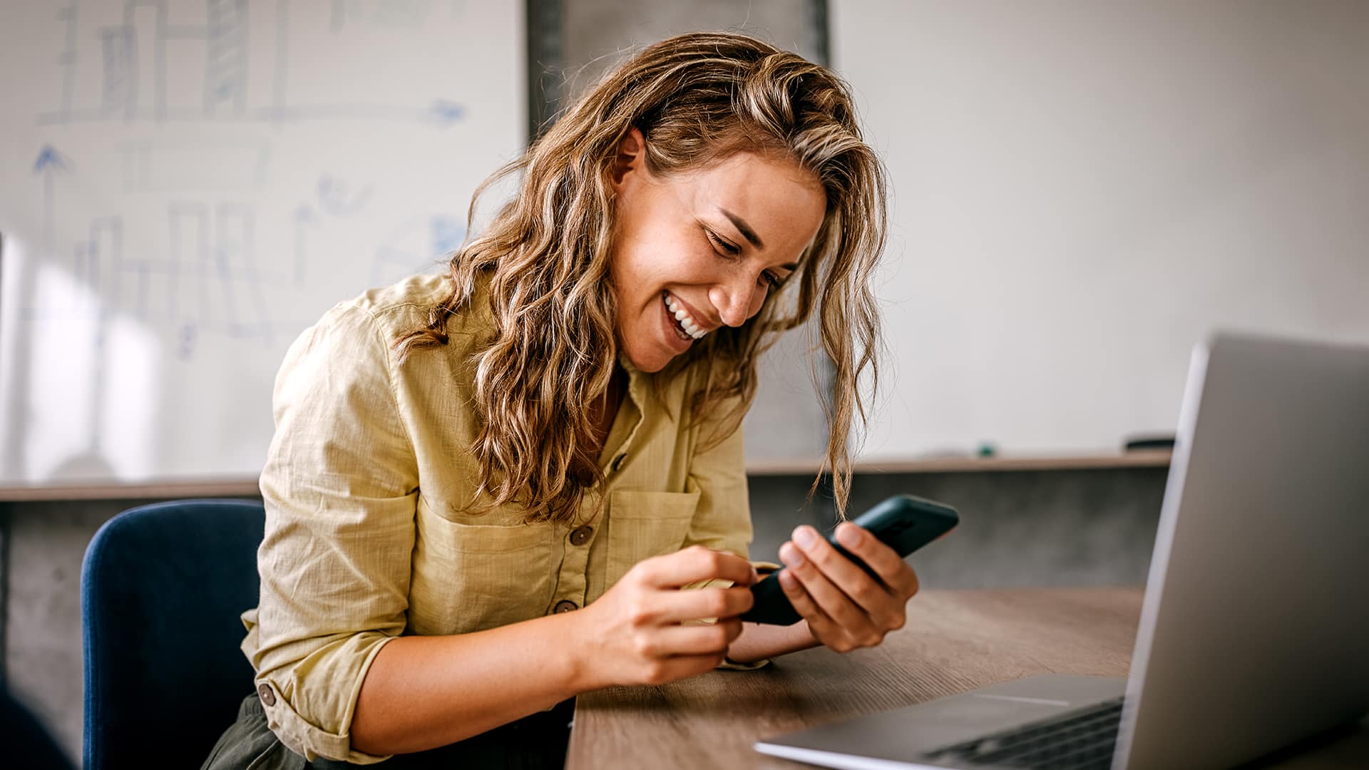 Women using smartphone and laptop laughing