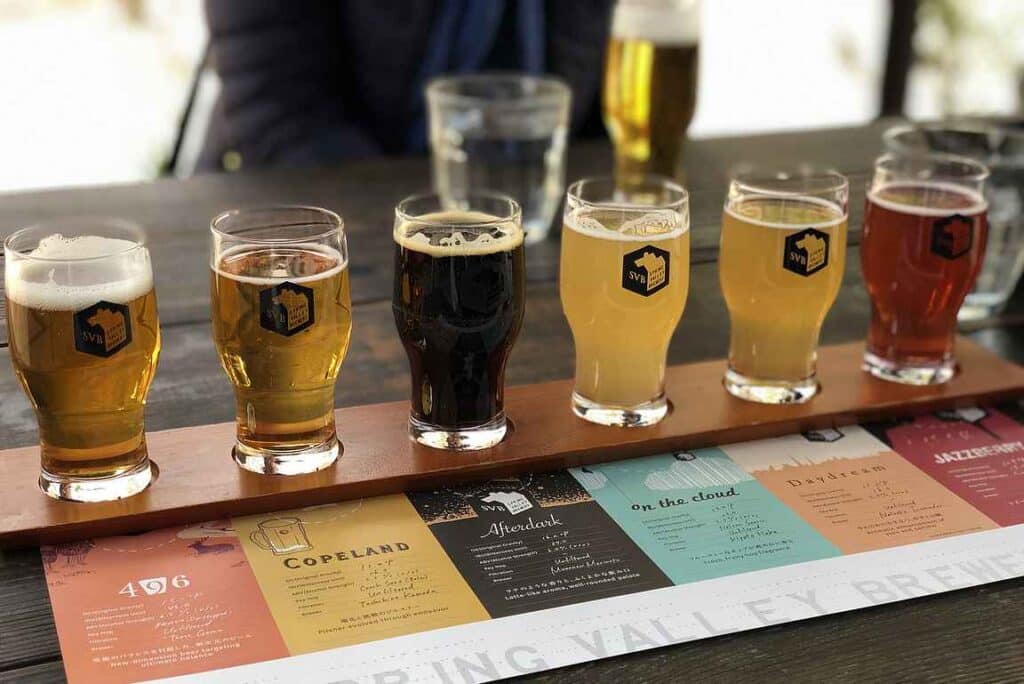 Valokuva olutmaistelusta. Rivi erivärisiä oluita ja esite niiden tiedoista.